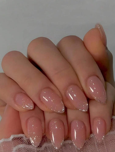Close-up of a hand with pink glittery nails on a neutral background