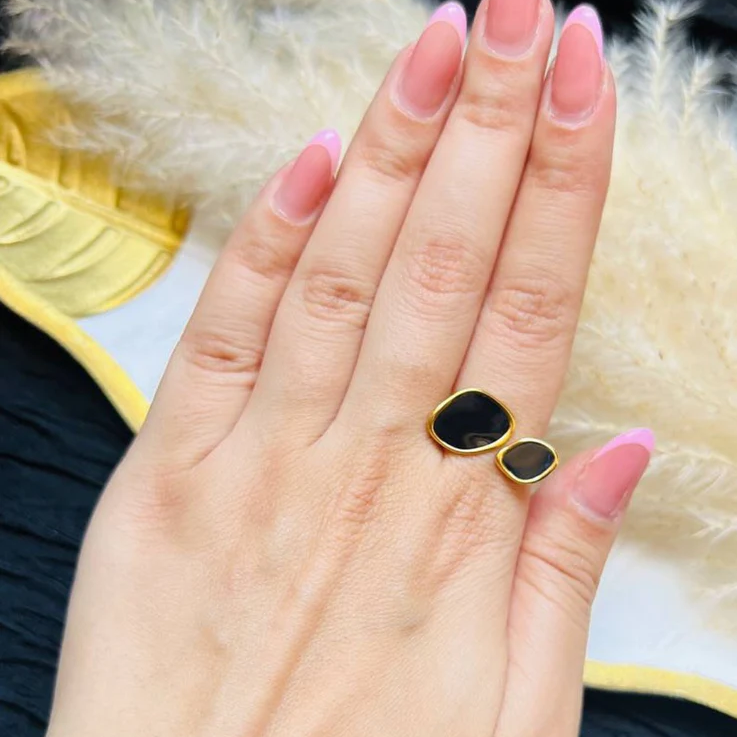 Hand wearing a black and gold ring with a soft focus background