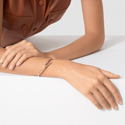 Close-up of a person's arm wearing a gold bracelet on a white background